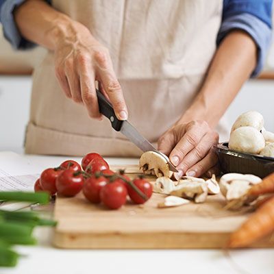 Hackar grönsaker med kniv i köket