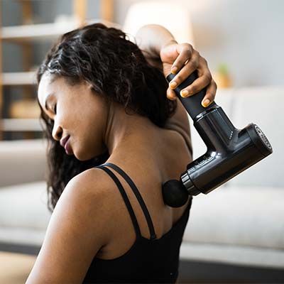 kvinna använder massagepistol efter träning